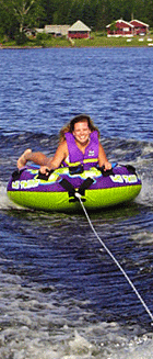 Photo of a smiling girl tubing on Wallace Pond in Canaan, VT (also known as Lake Wallace).  Jackson's Lodge and Log Cabins is in the background.