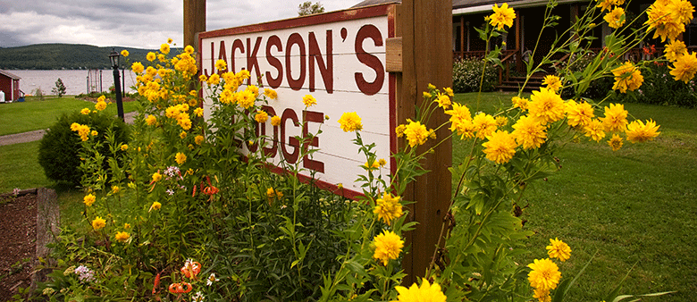 Flowers bloom around the sign welcoming visitors to Jackson's Lodge and Log Cabins - Your Vermont Wedding Destination - Don Whipple Photgraphy