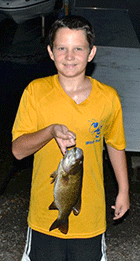 A young angler proudly displays his catch of the day - Click for larger image.