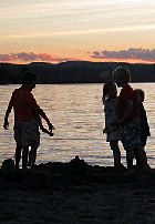 Children playing on Jackson's sandy beach as the sun sets.