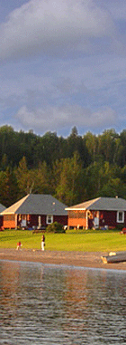 The light from a beautiful sunset shines on Jackson's Lodge and Log Cabins in Vermont's Northeast Kingdom as children have fun playing on the sandy beach